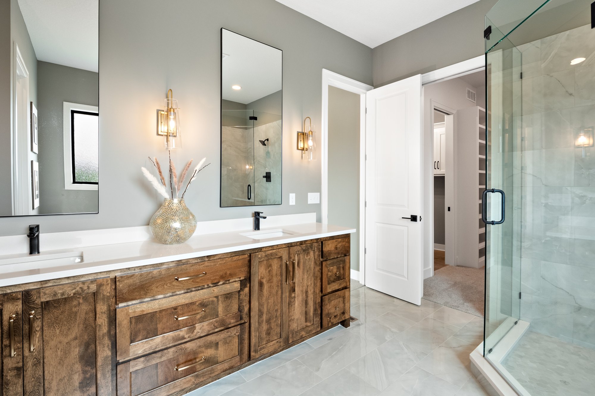 Primary bathroom in a Dusty Rhodes Homes custom home in the Kansas City area, with a wood double vanity and glass-enclosed shower.