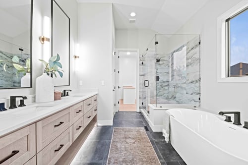 Image of a remodeled primary bathroom in Overland Park, Kansas, with a glass walk-in shower, dual vanities, and a garden tub. 
